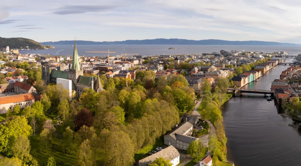 Flyfoto av sentrum med Nidarosdomen og fjorden. Bildet er brukt som illustrasjon i artikkel om hva det koster med en eiendomsmegler i Trondheim for ulike boligtyper og bydeler.